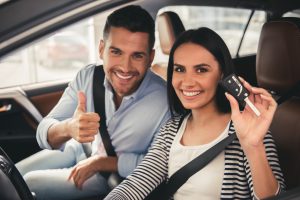 Happy couple sitting in new car holding the key