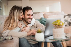 About us Young couple relaxing on couch with laptop. Love, happiness, people and fun concept